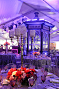 婚礼布置-简单华丽的婚宴场地布置:水晶台灯同洋红色的桌花辉映，加上蓝色的氛围灯光