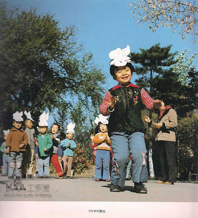 小朋友们在老师的引导下玩扮兔子竞走游戏。