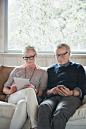 "Mature couple with grey hair looking at digital tablet and phone at home" by Stocksy Contributor "Trinette Reed"