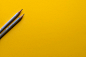 黄色表面上的两支灰色铅笔