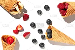 白色背景上的甜筒冰淇淋里的各种夏季水果。草莓，蓝莓，覆盆子，香蕉片放在华夫饼杯里。夏日甜菜单概念平铺