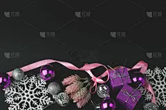 黑色的节日背景搭配白色和紫色的物品——紫色包装的圣诞礼物、闪闪发光的白色雪花、松枝和粉色丝带