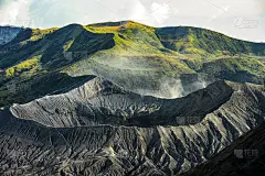 从上面看，令人惊叹的溴山火山口的特写前景和美丽的绿色山丘被夕阳照亮的背景。