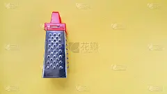 手动厨房刨丝器，红色手柄，黄色背景。复制文本的空间。厨房设置。烹饪概念。关于作业的概念。食物食谱的背