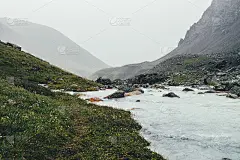 大气景观与山溪之间的冰碛在雨天。岩石间乳白色河流的荒凉景色。山河景色暗淡。乳水溪流中有苔藓和地衣的石