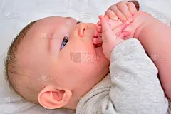 快乐的婴儿男婴把他的腿拉进他的嘴和微笑。四个月大的孩子，特写