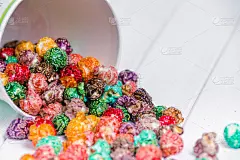 色彩鲜艳的糖果爆米花，白色背景。水平图像的垃圾食品，水果味爆米花在浅粉色的碗。五颜六色的，彩虹的，糖
