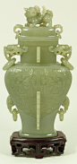 CHINESE GREENISH GREY JADE JAR WITH FOO DOG Of flattened baluster form, carved with archaistic dragons on shaped panels divided by a row of flanges, the shoulders carved with masks and loose ring handles, cover with Buddhistic lion finial. Includes fitted