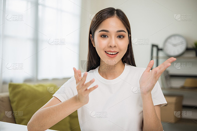 年轻的亚洲妇女看着摄像机视频会议在线坐在...