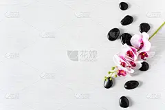 黑色的温泉石头与兰花花顶视图在白色木制背景。