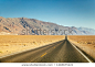 Classic panorama view of an endless straight road running through the barren scenery of the American Southwest in summer