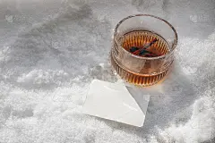 冬季早餐静物场景。一杯雪堆里的健康肉桂茶。空白名片模型。在阳光下白色的闪闪发光的雪背景。圣诞节的饮料
