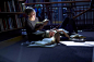 Female student lying on floor in a library with friend reaing book图片素材