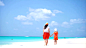 热带海滩上可爱的小女孩和年轻的母亲。两口之家在暑假里玩得很开心