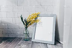 相框和一个小瓶子，在砖墙的背景上有含羞草。