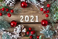 新年组成。圣诞花环与冷杉枝装饰在旧的深色木制背景与2021字母文字，平铺顶视图