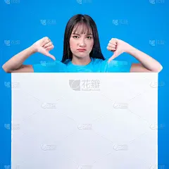 漂亮的亚洲年轻女子，刘海发型，蓝色t恤显示她的拇指倒过来，显示她的不喜欢，不赞成，和不赞成空白空白白