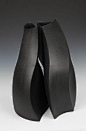 This may contain: two black vases sitting next to each other