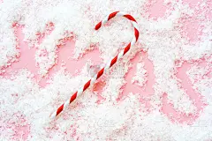 圣诞条纹藤铅笔在粉红色的人造雪的背景和题词圣诞