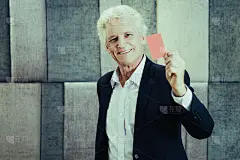 微笑的资深白人商人或裁判出示红牌阻止商业冲突。自信的企业家拿着名片，看着镜头