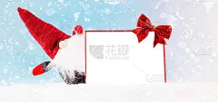 一个戴着红色帽子的侏儒在蓝色背景上持有一个文本框架。副本的空间。新年贺卡的背景。圣诞家居装饰。简单的