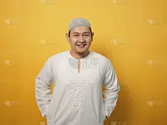 快乐的年轻亚洲穆斯林男子微笑着摆姿势拍照，黄色背景