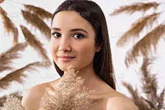 一个美丽的女孩在灰色的背景与干燥的潘帕斯草芦苇。白色背景上的芦苇草。美丽、水疗和自然装饰的概念