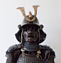 武士大铠。带一个放小旗（指物）的挂包钩 - 日本 - 17 世纪（江户时代） - Catawiki : 深棕色赤胴铠。
有双重胸甲（kurozome nimaido）和五重头盔（zunari-kabuto）。
头盔上带有风格化的飞鹿（锹形虫）角和锥形的前部装饰（maedate），上面有一个红色的”義“字（正义） 
面具为深棕色漆面，带有一个很宽的鼻子（menpo）。 
胸甲的背面带有 gattari 和 machi-uke 用于固定靠旗（指物）。

储存箱带有作为家族徽章的 tomeo-mon 。
储存箱