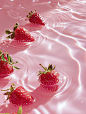 This may contain: several strawberries floating in the water on a pink surface with ripples around them