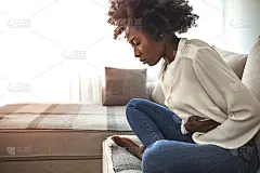 女人坐在床上，肚子疼。