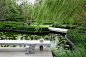 This may contain: a bench sitting on top of a wooden platform next to a pond filled with water lilies