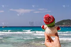 圣诞快乐的雪人戴着圣诞老人的帽子在阳光明媚的海滩上，新年假期概念休闲旅游在炎热的南方国家