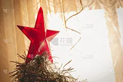 装饰圣诞树。圣诞树顶上的大红星。柔和的聚焦在从窗户射进来的阳光上。