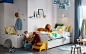 在蓝色、白色和黄色丛林主题儿童卧室里，摆放着 SLÄKT 斯莱克 床，配有拉出式床和储物空间。