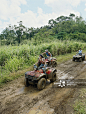 Group of friends riding ATVs down muddy dirt road (blurred motion)_创意图片