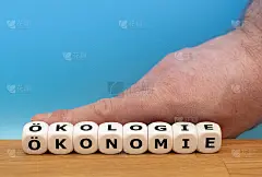 手在摇骰子，把德语单词“ÖKONOMIE”变成了“ÖKOLOGIE”(英语中“经济”变成了“生态”)