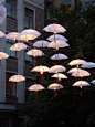Tiny umbrellas attached to twinkling lights for outdoor fete.