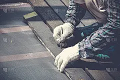 木匠的手或工人的手，用木工铅笔记号笔在木板上做记号。