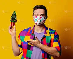 穿着90年代衬衫和面具的时尚男，黄色背景是圣诞树