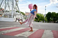 年轻的胖女人拿着棉花糖走在城市人行横道上
