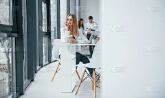 一个女人拿着笔记本电脑坐在一群年轻成功的团队前，在办公室里一起工作和交流