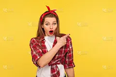 哇,很棒的广告!肖像惊讶的迷人的海报女孩指向空的墙壁，看着惊讶
