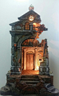 This may contain: a small clock tower is lit up in the middle of a room with stone steps