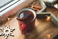 红色杯子里的肉桂红茶，点缀着冬日的装饰和灯光。舒适的冬季静物生活。