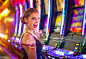 Young happy woman at a casino playing with slot machines : Stock Photo