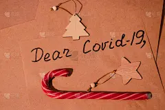在牛皮纸特写上写亲爱的COVID-19。圣诞祝福信用红色糖果和新年、圣诞木元素