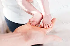 小婴儿的脚放在她爸爸的手上