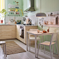 A small, beige, green and white kitchen with white MELLTORP table and two stackable TEODORES chairs.