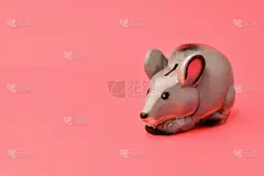 灰色的小猪储蓄罐以老鼠的形式站在右边，以粉红色为背景。摄影水平