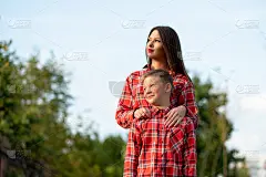 妈妈站在儿子身后，扶着他的肩膀，两眼都往旁边看。